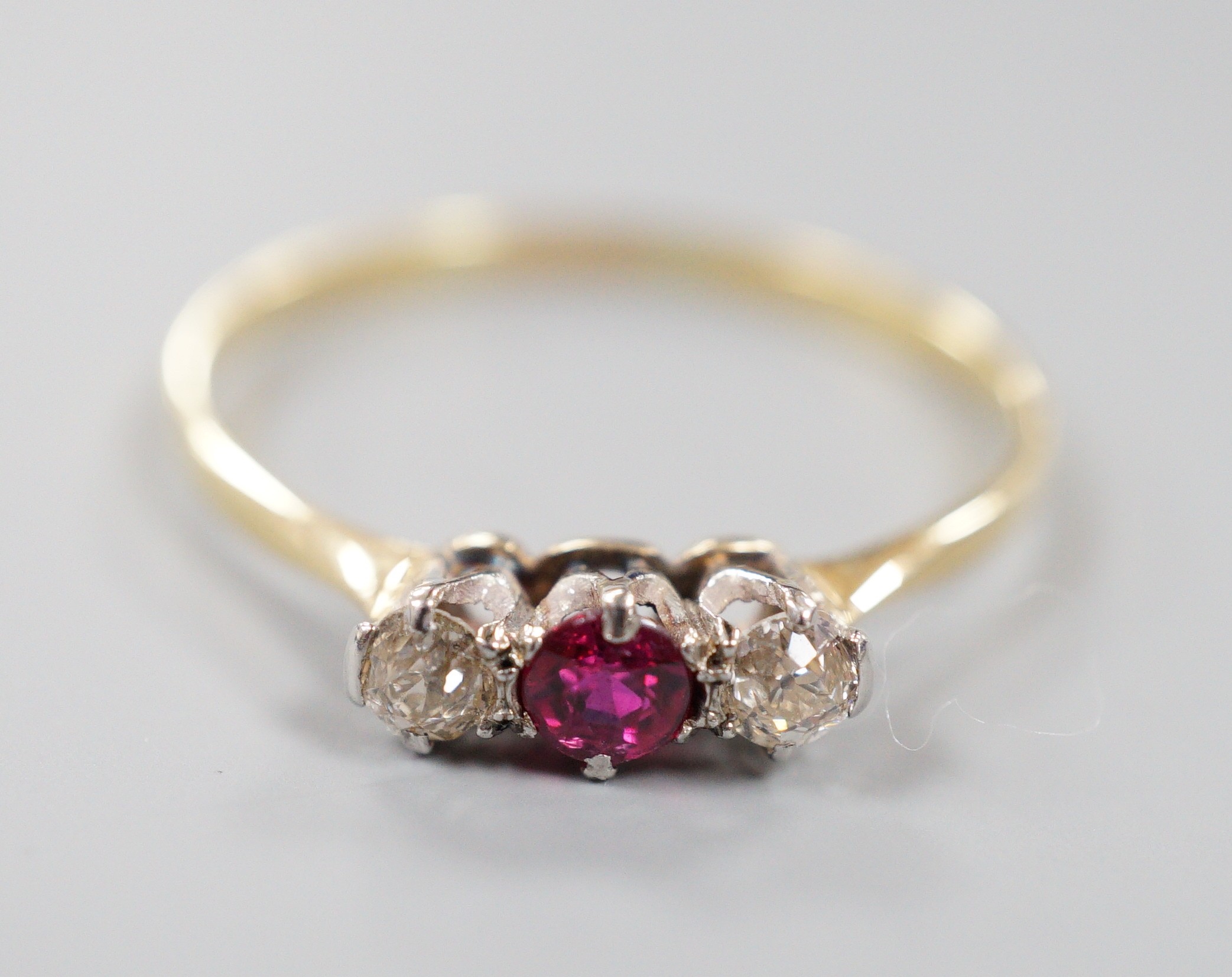 An 18ct, ruby and diamond set three stone ring, size V, gross weight 1.7 grams.